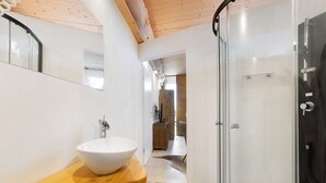 Ein modernes Badezimmer mit einem Holzbadezimmermöbel, einem weißen Waschbecken und einer Duschkabine aus Glas.