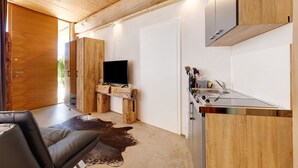 Une cuisine moderne dotée d’une cuisinière intégrée, d’un téléviseur à écran plat et de meubles de rangement en bois.
