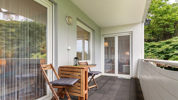 A covered outdoor area with a wooden table and chairs, a lantern, and a view of greenery. - "Am Paradies" Apartment – Relaxation in Baden-Baden (Baden-Baden)