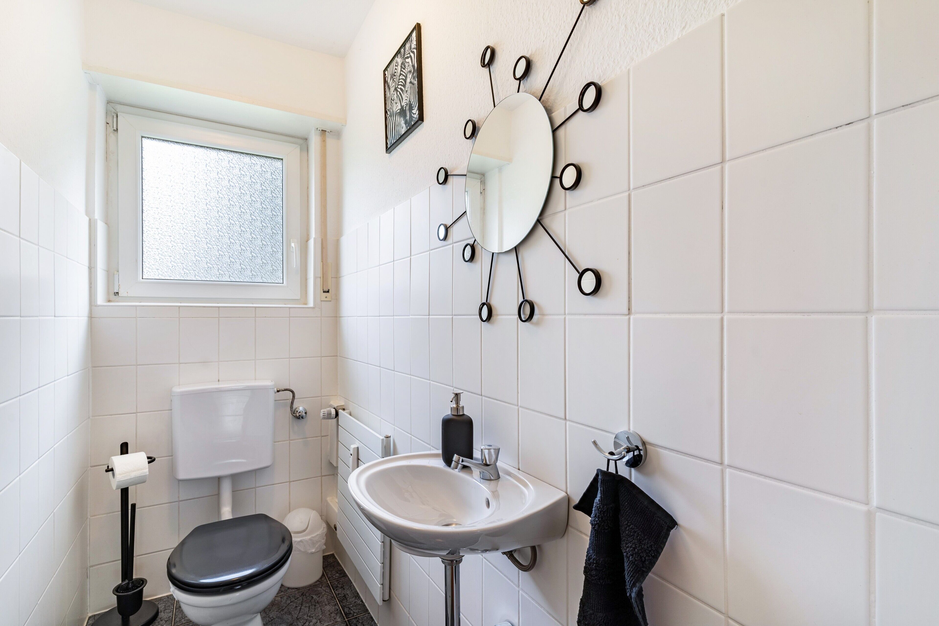 Un baño con inodoro, lavamanos, espejo y ventana.