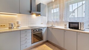 A modern kitchen with white cabinets, a built-in oven, a microwave, and a coffee maker. - "Am Paradies" Apartment – Relaxation in Baden-Baden (Baden-Baden)