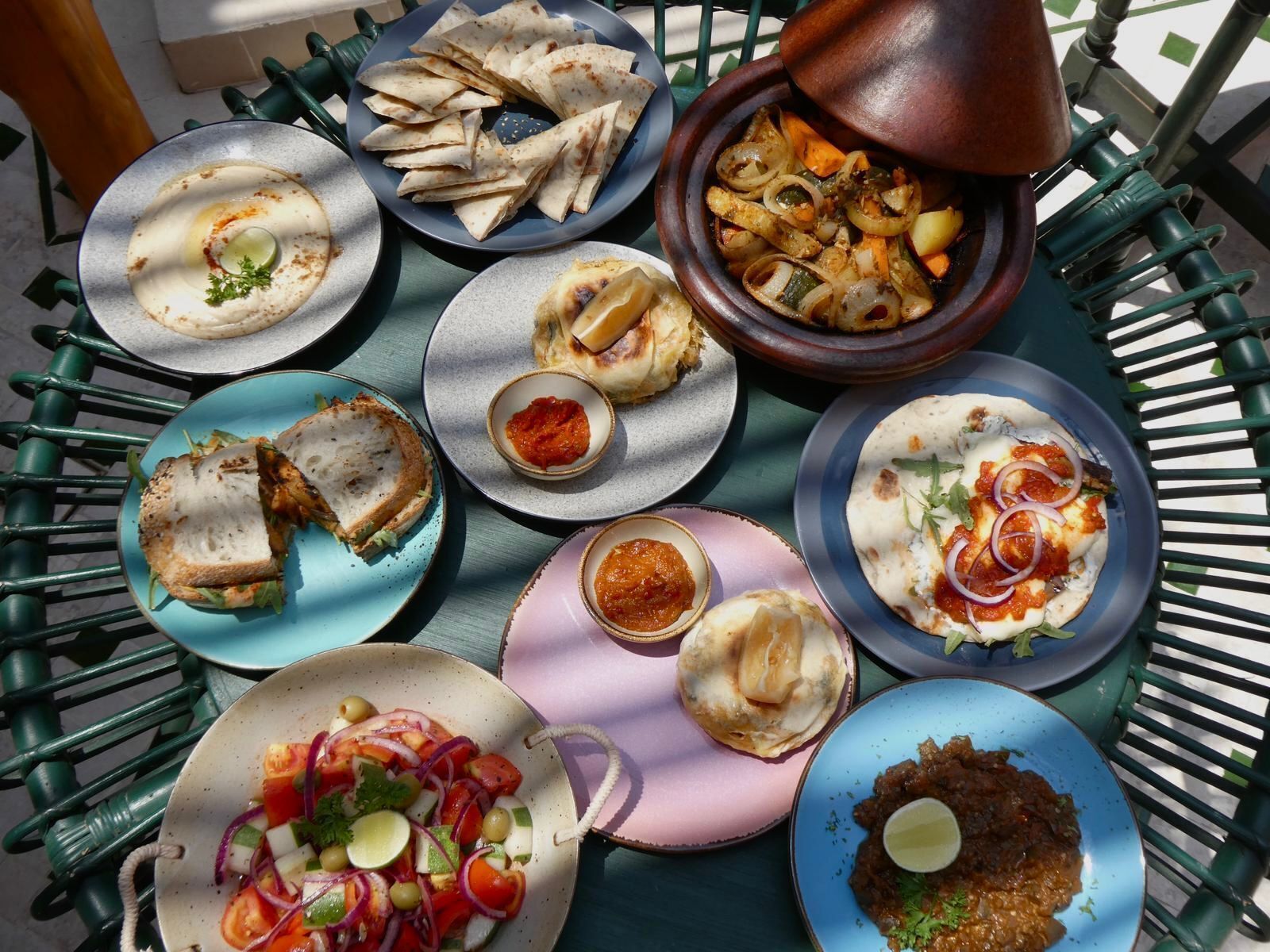 A variety of dishes on a table, including flatbreads, a salad, and a stew.