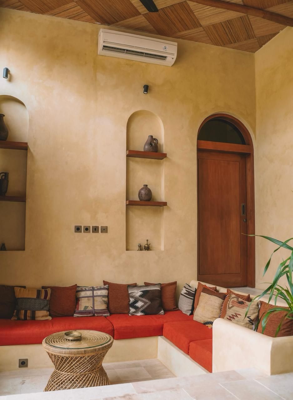 Una sala de estar acogedora con techo de madera, un sofá rojo, una mesita de mimbre y una puerta de madera.