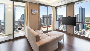A modern hotel room with a large window, a sofa, and a flat-screen TV.