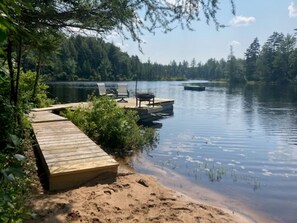 A wooden dock extending into a calm lake, surrounded by dense forest.