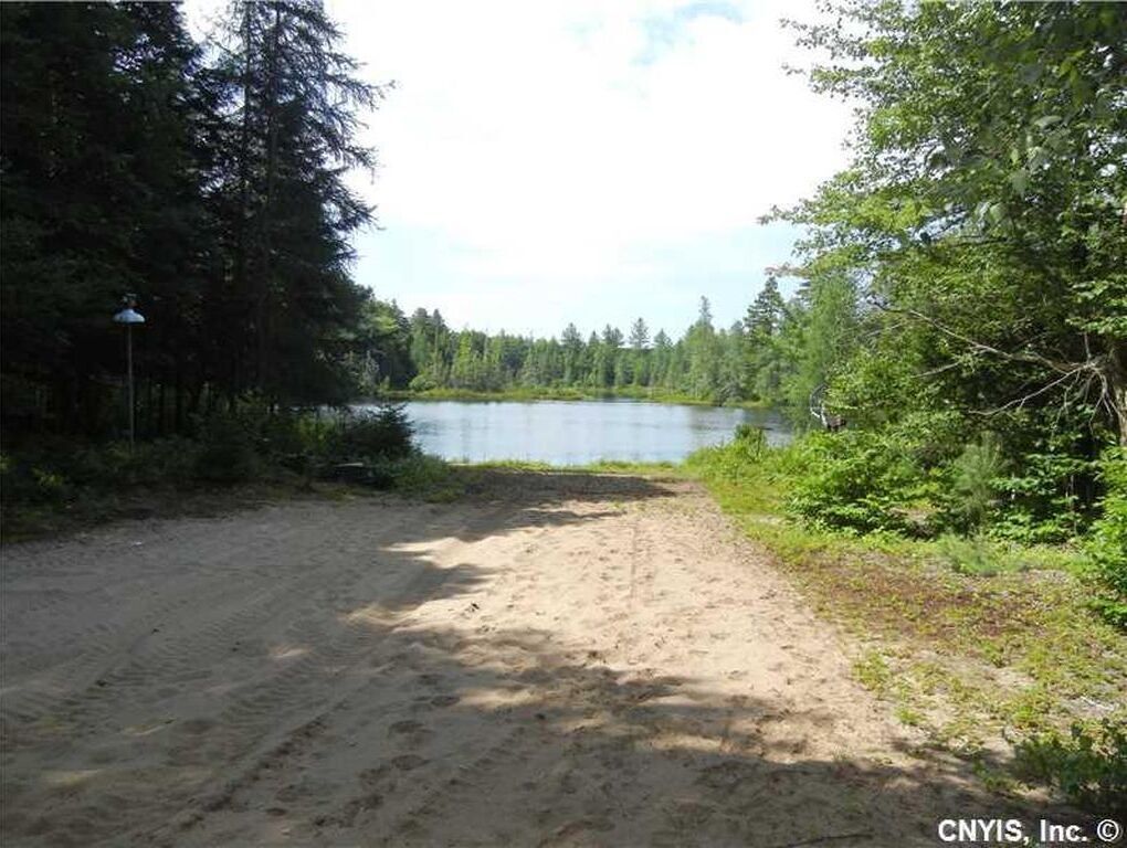 Une plage de sable qui mène à un lac bordé d’une forêt dense.