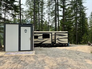 A recreational vehicle (RV) with a 'Premier' logo parked in a forested area.