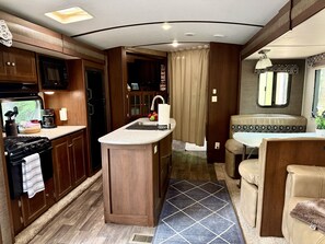 A compact RV kitchen with a stove, sink, and a small dining area.