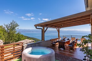 A terrace with a hot tub, outdoor seating, and a view of the sea.