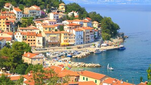 Une ville côtière avec des bâtiments le long du front de mer, un port de plaisance avec des bateaux et une vue dégagée sur la mer.