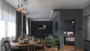 Un salon moderne avec un coin repas, des murs gris et un téléviseur diffusant Netflix.