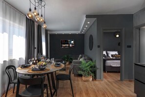 A modern living room with a dining area, grey walls, and a TV displaying Netflix.