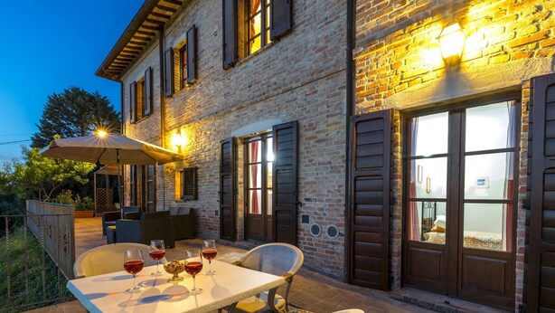 An outdoor dining area with a table, chairs, and wine glasses.