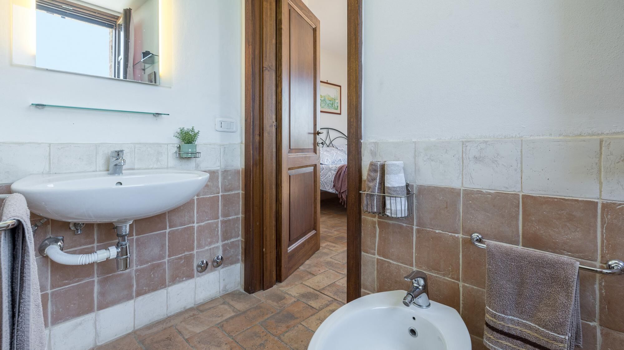 A bathroom with a sink, bidet, and bathtub. There is a towel rack and a mirror above the sink.