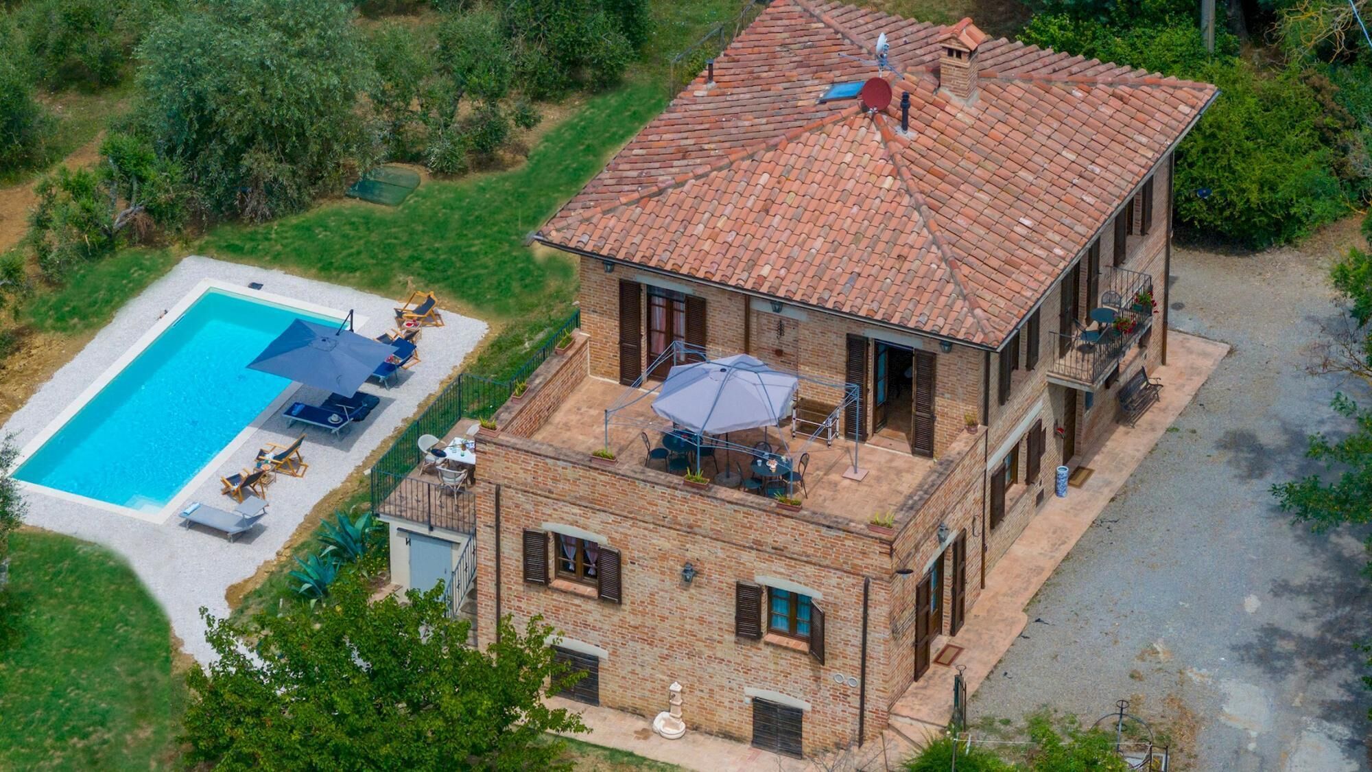 Ein zweistöckiges Haus mit Swimmingpool, Sitzgelegenheiten im Freien und einem Balkon.