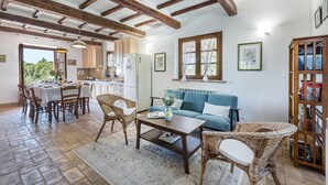 A cozy living room with a sofa, wicker chairs, a coffee table, and a dining area with a table set for four.