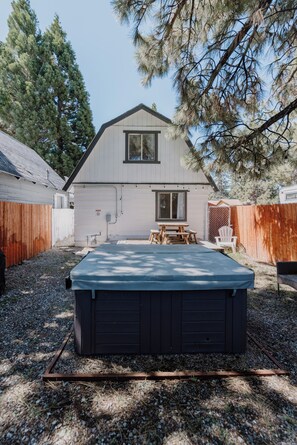 Ett hus med en trädgård, en bubbelpool och en träaltan.