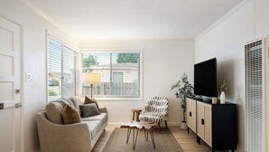 A living room with a sofa, a coffee table, a TV, and a cabinet. - Scenic Oasis: King Bed Suite & Panoramic Views & Ultra Fast Fiber WiFi  (SAN DIEGO)