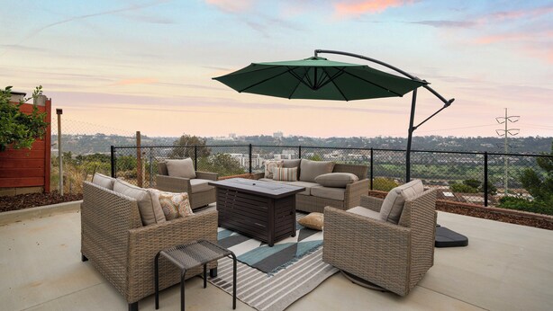 An outdoor patio with wicker furniture, a coffee table, and a green umbrella. - Scenic Oasis: King Bed Suite & Panoramic Views & Ultra Fast Fiber WiFi  (SAN DIEGO)