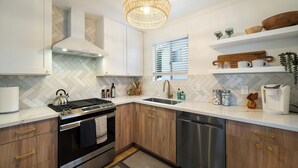 A modern kitchen with wooden cabinets, stainless steel appliances, and a herringbone tile backsplash. - Scenic Oasis: King Bed Suite & Panoramic Views & Ultra Fast Fiber WiFi  (SAN DIEGO)