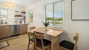 A modern kitchen with wooden cabinets, a stainless steel dishwasher, and a dining area with a wooden table and chairs. - Scenic Oasis: King Bed Suite & Panoramic Views & Ultra Fast Fiber WiFi  (SAN DIEGO)
