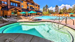A pool area with lounge chairs and umbrellas, a wooden building with balconies, and a clear sky. - Luxury @Heavenly, Pool, Hot Tub, 6 Beds, Game Room (South Lake Tahoe)