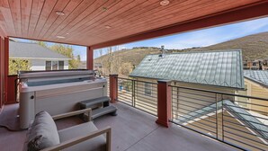 A covered outdoor area with a hot tub, seating, and a view of a house and hills. - Mountain Nirvana| Hot Tub | Walk to Ski & Main St. (Park City)