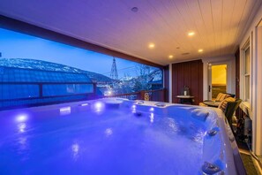 A hot tub with a view of a snowy landscape and a power line tower.