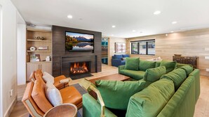 A modern living room with a fireplace, green sofa, leather chairs, and a television mounted on the wall. - Mountain Nirvana| Hot Tub | Walk to Ski & Main St. (Park City)