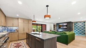 A modern kitchen with wooden cabinets, a central island, and pendant lighting. - Mountain Nirvana| Hot Tub | Walk to Ski & Main St. (Park City)