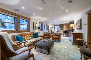 A spacious living room with a large window, a sofa, a coffee table, and a fireplace.