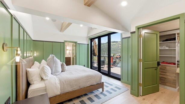 A bedroom with a bed, a bedside table, a wardrobe, and a sliding glass door leading to an outdoor area. - Mountain Nirvana| Hot Tub | Walk to Ski & Main St. (Park City)