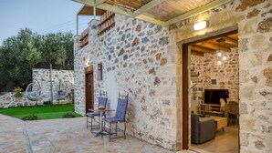 A stone building with a stone patio, outdoor seating, and a TV in the interior. - Stoney Villa Koxari By Estia (Hersonissos)