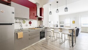 Une cuisine moderne équipée d’un réfrigérateur en acier inoxydable, d’un four encastré et d’une cuisinière à gaz. On y trouve également des tabourets de bar et une table à manger dans l’espace repas attenant.