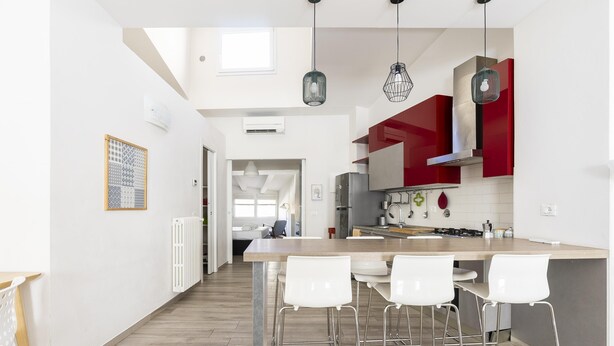 Une cuisine moderne dotée d’un îlot central, de tabourets de bar et de luminaires suspendus.