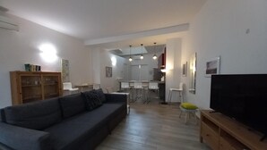 Un salon moderne avec un canapé gris, un meuble en bois et un téléviseur posé sur un support en bois.