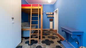 Een kamer met een stapelbed, een ladder, een boekenplank en een bureau.