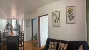 A modern living room with a black sofa, a dining table with chairs, and a kitchen area in the background. - coati del arenal (La Fortuna)