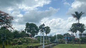 A park with a pathway, palm trees, and a fountain. - coati del arenal (La Fortuna)