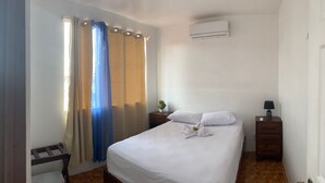 A hotel room with a bed, a nightstand, a lamp, and an air conditioning unit. - coati del arenal (La Fortuna)