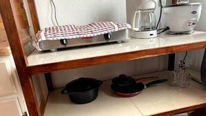A kitchen with a coffee maker, toaster, and kettle on a countertop. There is a pot and pan on the lower shelf. - coati del arenal (La Fortuna)