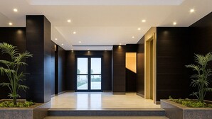 A modern interior with a staircase leading to a glass door entrance, dark walls, and potted plants. - Family Getaway Chalet in Port Said (Port Said Governorate)