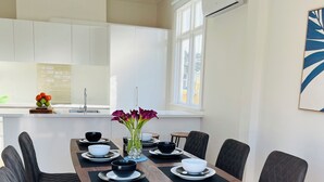 A modern dining area with a wooden table, black chairs, and a vase of flowers. - Luxurious House Next to St Clair Beach (Dunedin)