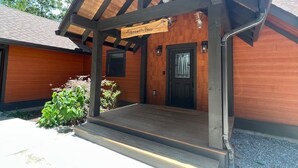 Ein Holzgebäude mit einer Veranda, einer schwarzen Tür und einem Schild mit der Aufschrift 'Tranquility Base'.