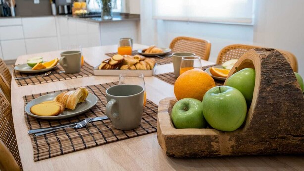 A breakfast table with croissants, apples, oranges, and a mug. - Monte Estoril Seabreeze by Portugal Portfolio (Estoril)