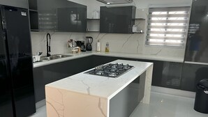 Une cuisine moderne dotée d’un îlot central, de meubles noirs et d’un réfrigérateur en acier inoxydable.