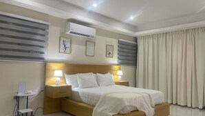 Une chambre d’hôtel moderne avec un lit en bois, deux tables de chevet avec des lampes, un appareil de climatisation et une fenêtre avec des rideaux.