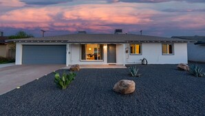 Una casa a un piano con garage, ingresso e vialetto.