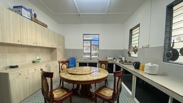Una cocina con una mesa redonda de madera, cuatro sillas, un ventanal y armarios.