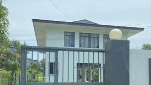 Una casa de dos pisos con fachada blanca y techo oscuro.